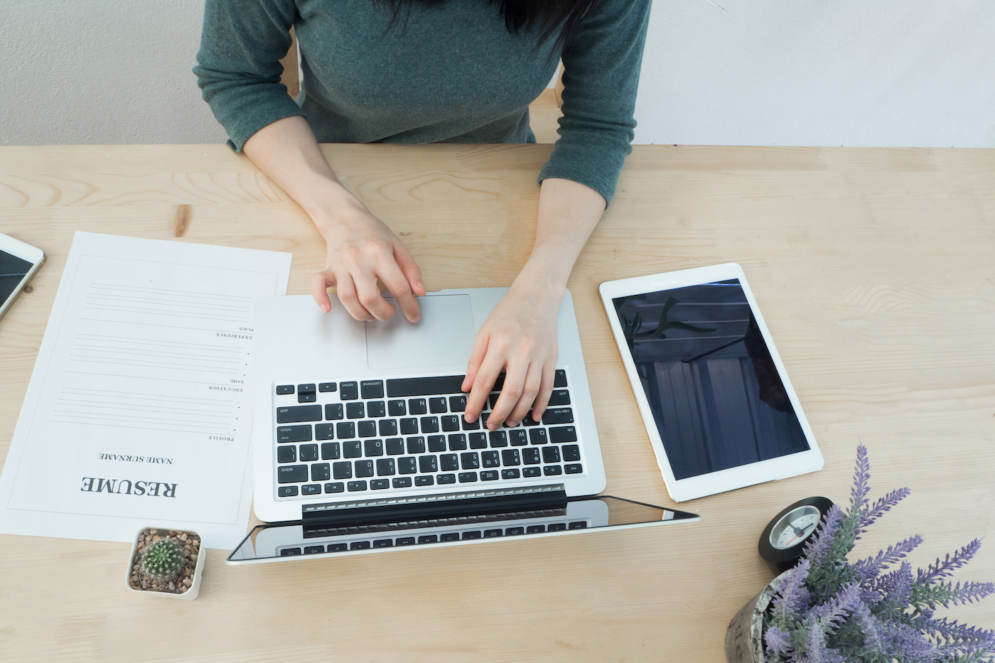 Office table with a resume and a woman’s hand typing on keyboard