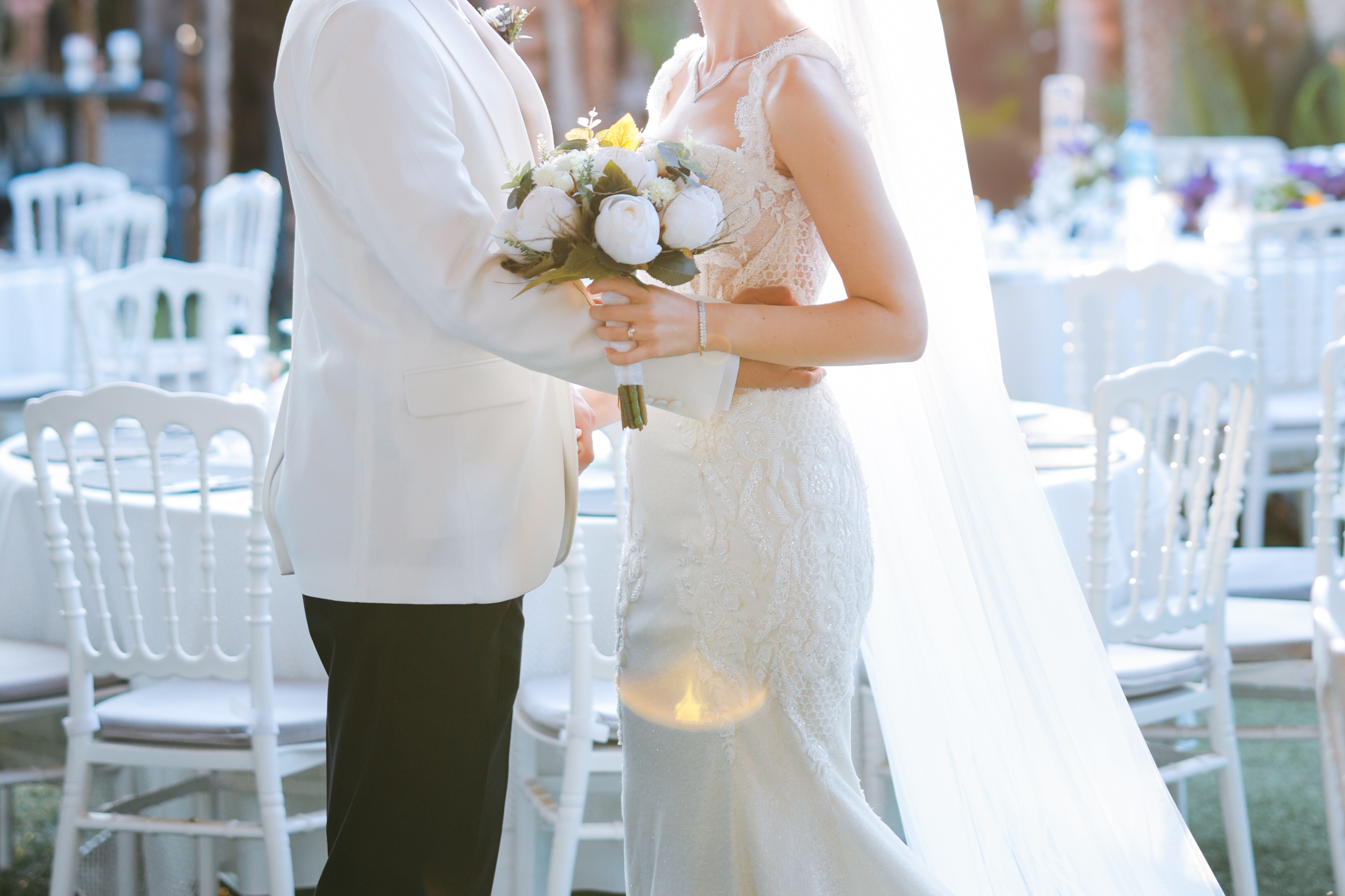 Man and woman holding each other waist  with a bouquet in a wedding ceremony