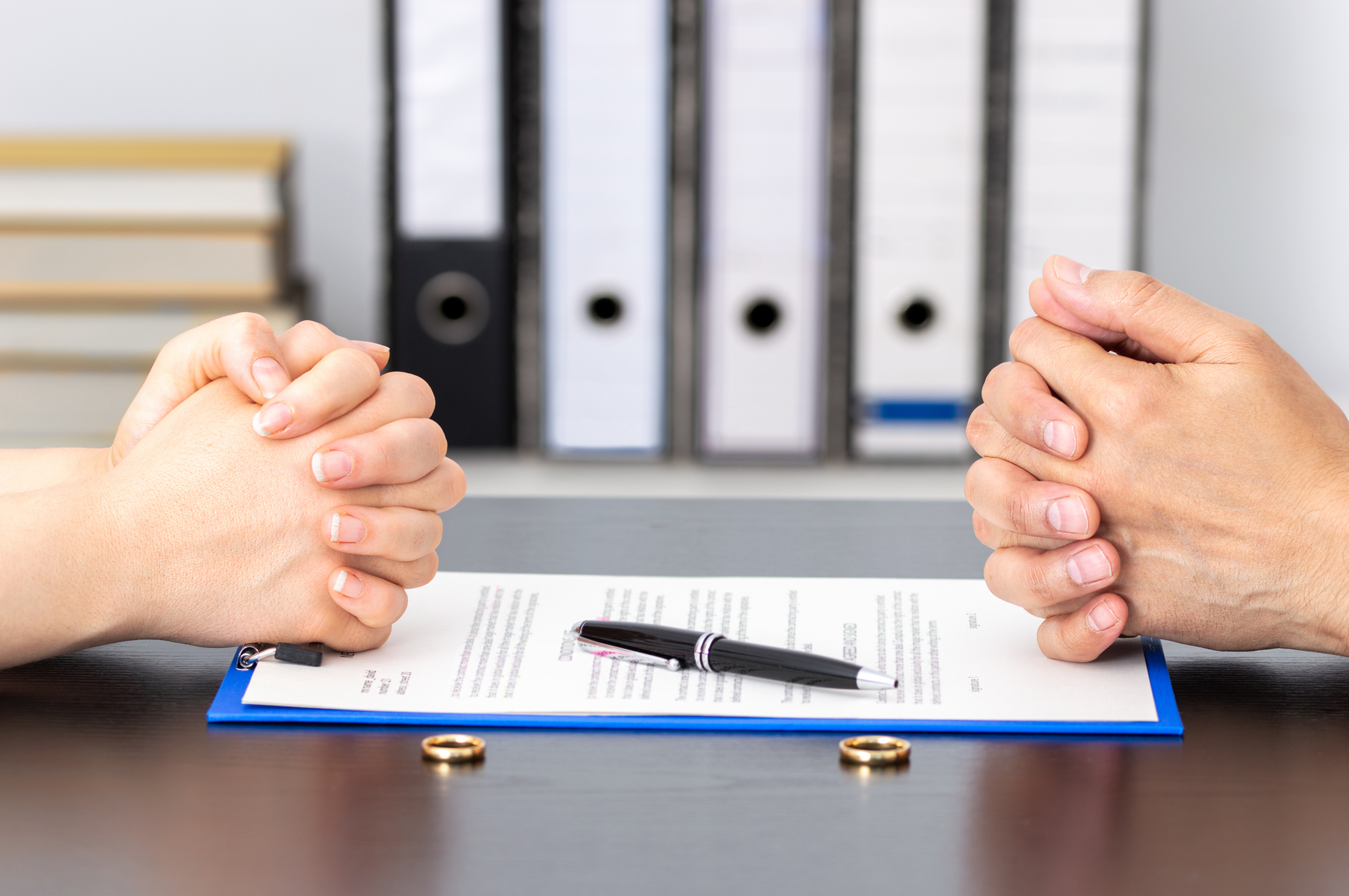 Couple negotiating with a paper and two rings on the table of a office