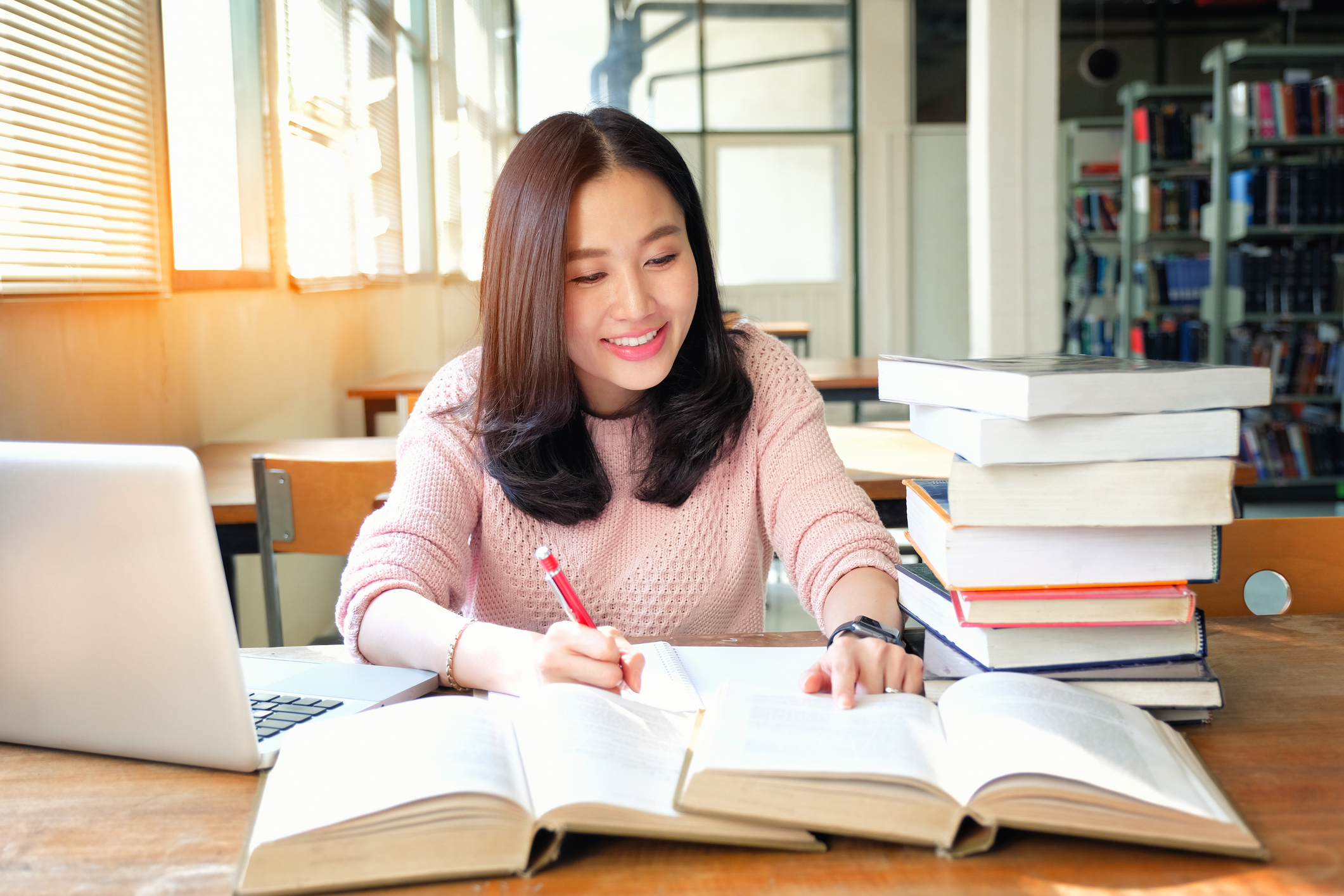 Woman reading books and studying, smiling at the camera