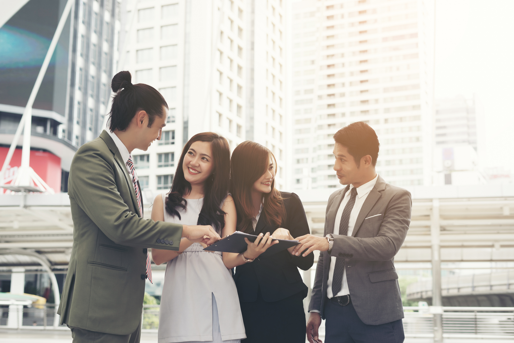 A group of people outdoors looking at each other in agreement pointing on a note board