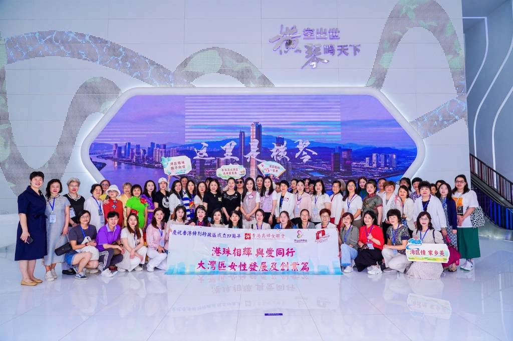 Group of women taking a photo with a banner in front of a LED screen