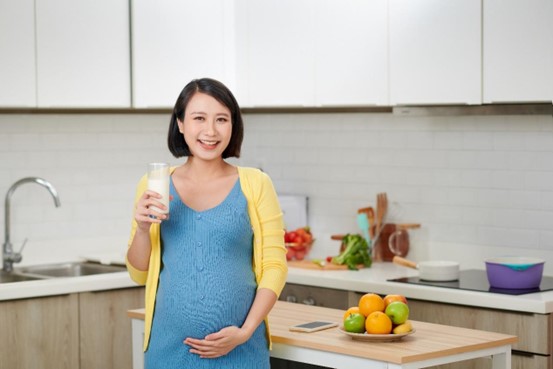 Pregnant woman holding a glass of milk in a kitchen