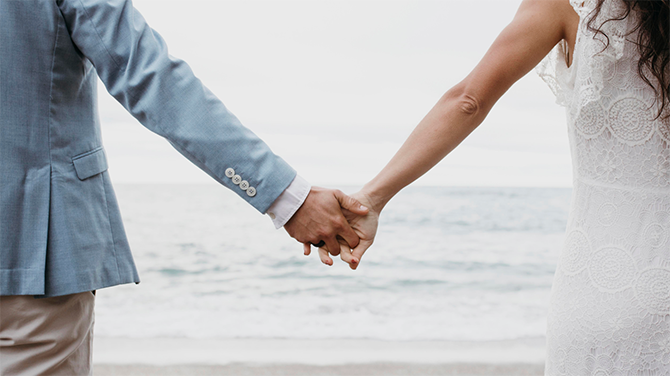 Man and woman holding hands by a beach