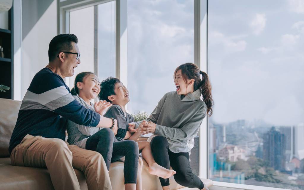 Father and mother laughing with two children in a living room