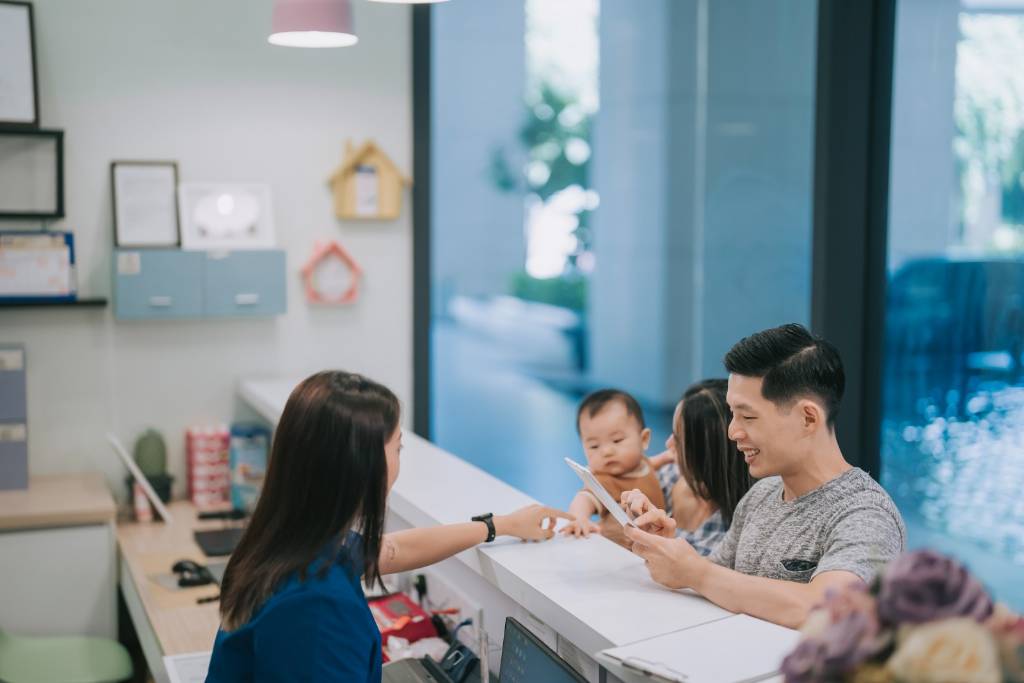 Parent hold a baby and consulting a staff in a child care centre